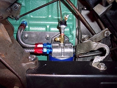  The original full-flow oil filter canister would not fit in the engine compartment, so a remote filter head is mounted on the rear of the block, above the oil pan.  This is a very tight fit and the inner (return) line is quite short.  The oil filter gauge mechanical sender is attached to a T fitting on the topy of the filter head (outflow side of filter) and an oil-pressure switch (for the electric chokes) is at the top of the T fitting